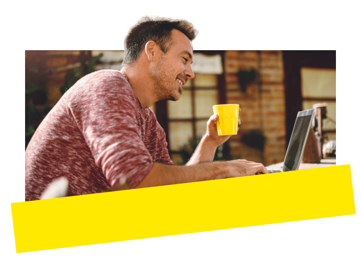 A man drinking coffee while working on a laptop