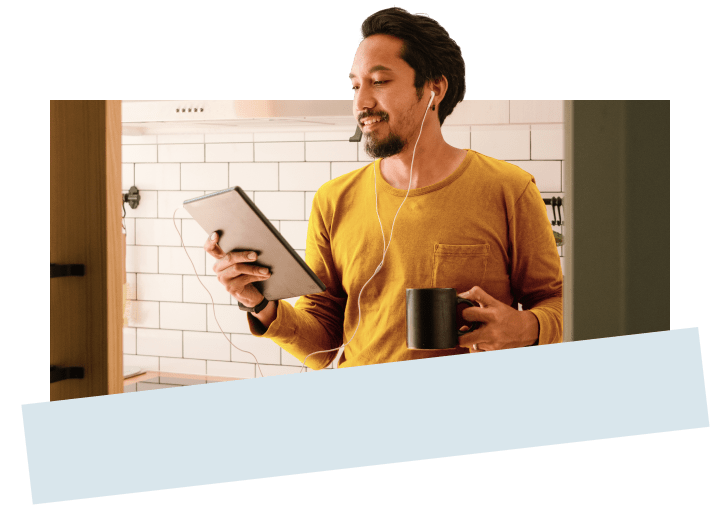A man wearing earbuds holding a tablet in one hand and a coffee in the other